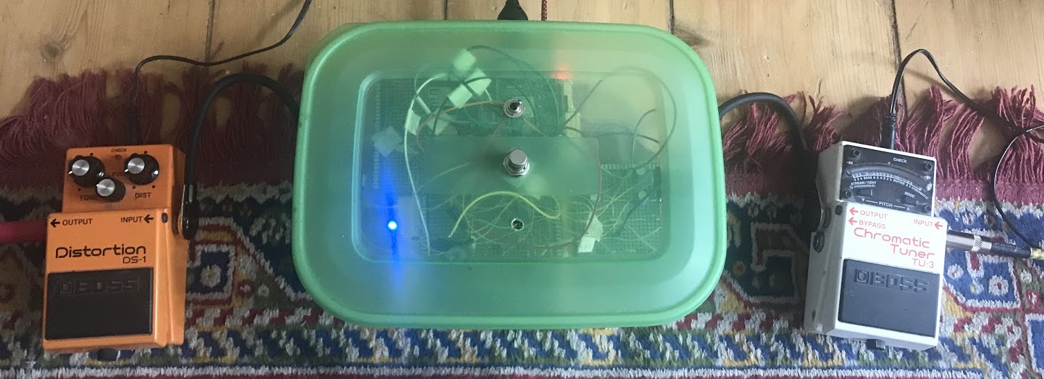 A chain of 3 effects pedals, connected on the floor